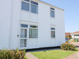 The exterior of a white building with windows and doors and some grass and plants outside at La Capsule in Dawlish Warren