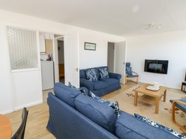 A living room with blue sofas a wooden coffee table and a wall-mounted television at La Capsule in Dawlish Warren