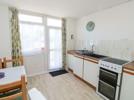 A kitchen with a stove sink wooden countertop and dining table near a window with curtains at La Capsule in Dawlish Warren