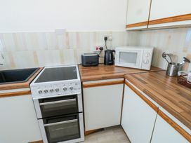 A kitchen corner with a sink stove toaster kettle microwave and utensils at La Capsule in Dawlish Warren