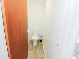 A small bathroom with a toilet brush a toilet and a wooden door at La Capsule in Dawlish Warren