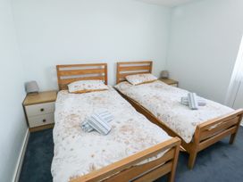 A bedroom with two single wooden beds with floral bedding and bedside tables with lamps at La Capsule in Dawlish Warren