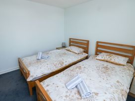 A bedroom with two single wooden beds with floral bedding and two rolled towels on each bed at La Capsule in Dawlish Warren