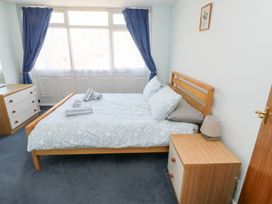 A bedroom with a double bed and blue curtains beside large windows at La Capsule in Dawlish Warren