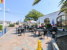 An outdoor seating area with tables chairs colorful umbrellas and string lights at La Capsule in Dawlish Warren
