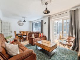 A living room with a sofa, dining table, and coffee table at Mylnebeck Lodge in Bowness-on-Windermere