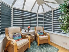 A conservatory with two armchairs and a coffee table at Mylnebeck Lodge in Bowness-on-Windermere