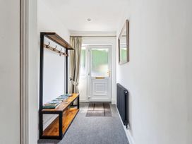 A hallway with a bench, coat hooks, and a door at Mylnebeck Lodge Bowness-on-Windermere