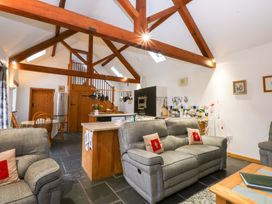 A living room with a sofa and kitchen island at Beudy Mawr Y Felinheli