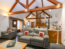 A living room with a sofa, armchairs, and a dining area at Beudy Mawr Y Felinheli