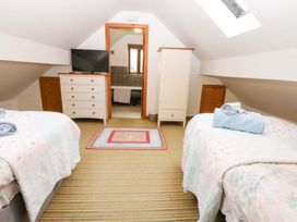 A bedroom with two beds and a television at Beudy Mawr Y Felinheli