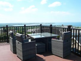A seating area with a table and chairs overlooking the sea at Maesawel Studio in Llanfair