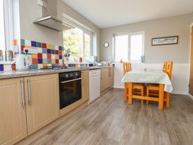 A kitchen with appliances and a table at The Farmhouse in Brynsiencyn near Newborough