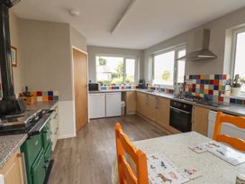 A kitchen with an oven and dining table at The Farmhouse in Brynsiencyn near Newborough