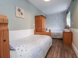 A bedroom with two beds and a wooden wardrobe at The Farmhouse in Brynsiencyn near Newborough