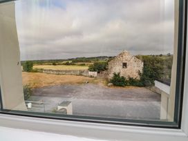 A view of a field and barn from a window at The Farmhouse in Brynsiencyn near Newborough