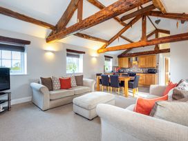 A living room with a sofa, television, and dining area at Carleton Mill Cottage in Carlisle