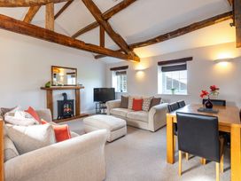 A living room with a sofa, fireplace and dining area at Carleton Mill Cottage in Carlisle