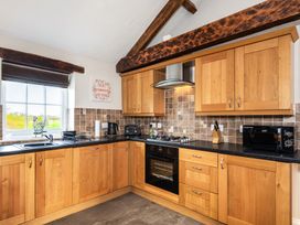 A kitchen with wooden cabinets and appliances at Carleton Mill Cottage in Carlisle