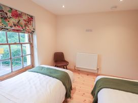 A bedroom with two beds and a chair at Rose Cottage in Crosby on Eden near Carlisle