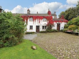 A house with ivy on the wall and a path in the garden at Mill Cottage in Garnett Bridge