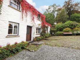 An outdoor view of a white house with plants and a gravel path at Mill Cottage in Garnett Bridge