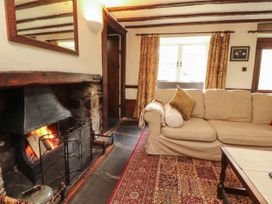 A living room with a fireplace and a sofa at Mill Cottage in Garnett Bridge