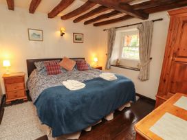 A bedroom with a bed nightstand and window at Mill Cottage in Garnett Bridge