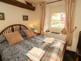 A bedroom with a bed and window at Mill Cottage in Garnett Bridge