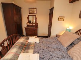 A bedroom with a bed and dresser at Mill Cottage in Garnett Bridge
