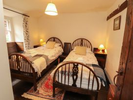 A bedroom with two beds and a window at Mill Cottage in Garnett Bridge
