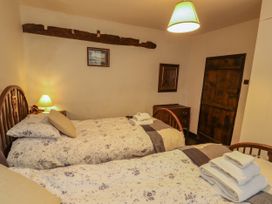 A bedroom with two beds and a lamp at Mill Cottage in Garnett Bridge
