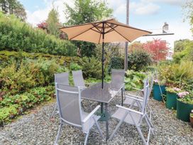 A garden with a table and chairs under an umbrella at Mill Cottage Garnett Bridge