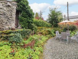 A garden with a stone wall and outdoor furniture at Mill Cottage in Garnett Bridge