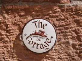 A sign with 'The Cottage' on a stone wall at Carwinley Mill House Cottage Longtown