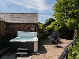 A garden with a hot tub and outdoor chair at Carwinley Mill House Cottage Longtown