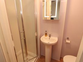 A bathroom with a shower, wash basin, mirror, and toilet at Archers in Keswick