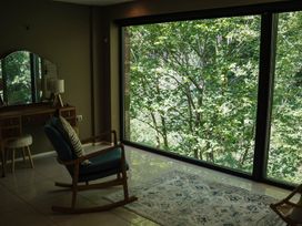 A living room with a rocking chair and window view at The Heronry in Longtown