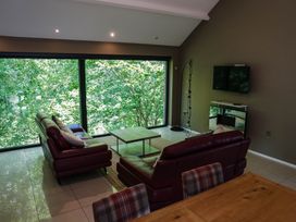 A living room with a television and large windows at The Heronry in Longtown