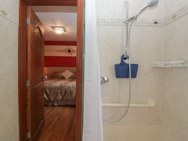 A bathroom with a shower and a door leading to a bedroom at Stonegarth Cottage in Grasmere