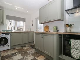 A kitchen with cabinets, sink, washing machine, and appliances at Fountain Cottage in Keswick