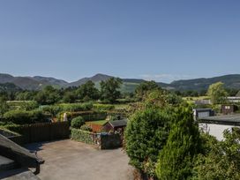 A view of a garden with trees and mountains in the background at Fountain Cottage in Keswick