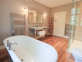 A bathroom with a bathtub mirror and sinks at Little Ellers in Portinscale near Keswick