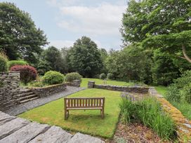 A garden with a bench and stone wall at Little Ellers in Portinscale near Keswick