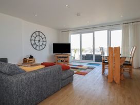 A living room with a sofa, TV, and dining area at The View in Newquay