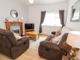 A living room with brown sofas a wooden coffee table a television and a fireplace at Fairways in Prestatyn
