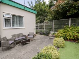 An outdoor patio with garden furniture and plants next to a house at Fairways in Prestatyn