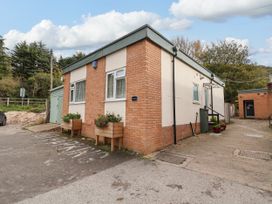 Exterior view of a single-story building with brick and cream walls a green shed and flower planters at Fairways in Prestatyn