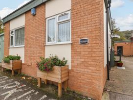 The exterior corner of a brick building with two windows and planters with flowers at Fairways in Prestatyn