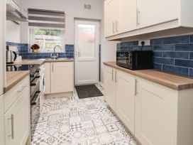 A kitchen with patterned floor tiles blue backsplash cabinets and appliances at Fairways in Prestatyn